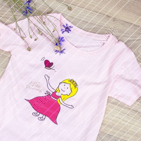 Auf einer Holzfläche liegt ein rosa T-Shirt mit dem Kleine Prinzessin-Design der Plotterbande.